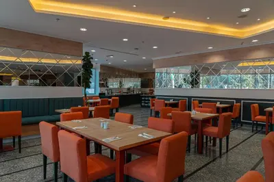 a restaurant with wooden tables and orange chairs at La Casa Hotel Amman by FHM in Amman