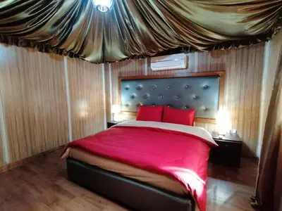 a bedroom with a large bed with red pillows at Sharah Luxury Camp in Wadi Rum