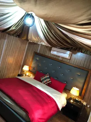 a bedroom with a large red bed with two lamps at Sharah Luxury Camp in Wadi Rum