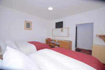 a bedroom with two beds and a desk with a tv on the wall at Petra Lion Hotel in Wadi Musa