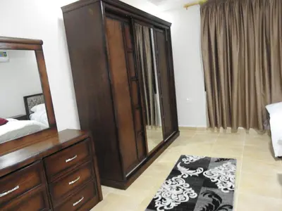 a bedroom with a large wooden dresser and a mirror at Amro Petra Apartment in Wadi Musa