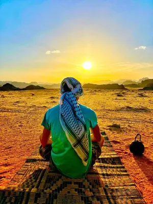 a man sitting in the desert watching the sunset at Wadi rum galaxy camp in Wadi Rum