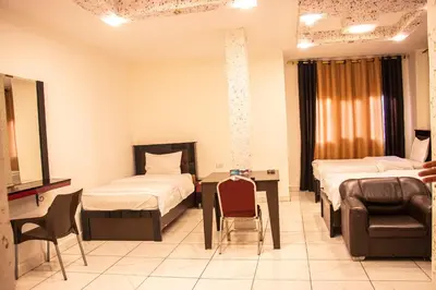 a hospital room with two beds and a table and chairs at Sara Crown Hotel in Irbid