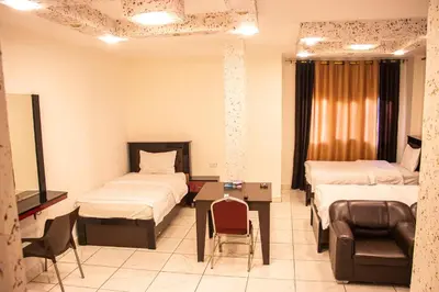 a room with two beds and a couch and a chair at Sara Crown Hotel in Irbid