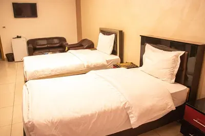 two beds in a hotel room with white sheets at Sara Crown Hotel in Irbid