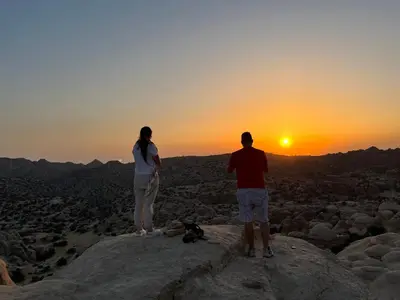 two people standing on a rock looking at the sunset at Al-Nawatef ECO camp- Dana Nature Reserve in Dana