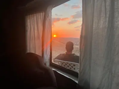 a man sitting in a window watching the sunset at Al-Nawatef ECO camp- Dana Nature Reserve in Dana