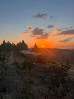 a sunset over a field with a group of tents at Al-Nawatef ECO camp- Dana Nature Reserve in Dana