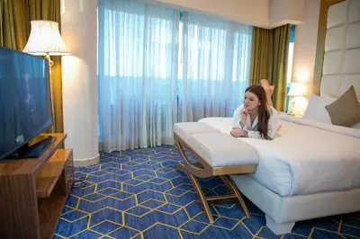 a woman sitting on a bed in a hotel room at Coral Tower Hotel by Hansa in Amman