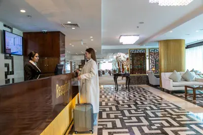 a woman with a suitcase standing at a counter in a store at Coral Tower Hotel by Hansa in Amman