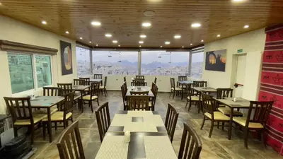 a restaurant with tables and chairs and a large window at Petra Sofsaf Hotel in Wadi Musa