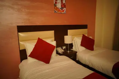 two beds with red pillows in a hotel room at Petra Sofsaf Hotel in Wadi Musa