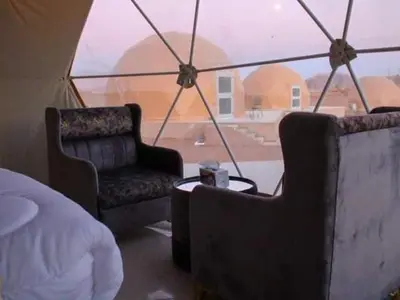 a room with two chairs and a bed and a tent at Wadi Rum Nova camp in Wadi Rum