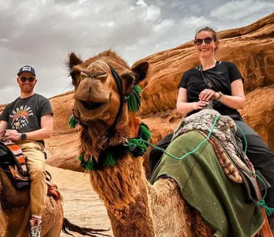 two people riding on a camel in the desert at Wadi Rum Nova camp in Wadi Rum