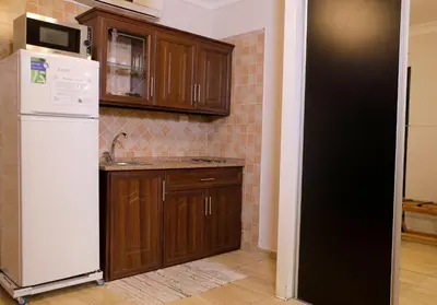 a kitchen with a white refrigerator and wooden cabinets at Abu Alsoud Hotel in Amman