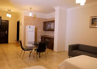a kitchen and living room with a table and chairs at Abu Alsoud Hotel in Amman