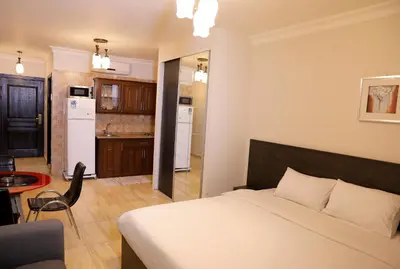 a bedroom with a white bed and a kitchen at Abu Alsoud Hotel in Amman