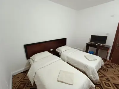 two beds with white sheets in a room at Happy Night Hostel in Wadi Musa