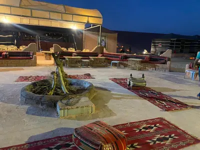 a patio with rugs and a fountain with a tree at Arena Desert Camp & Adventurers in Wadi Rum