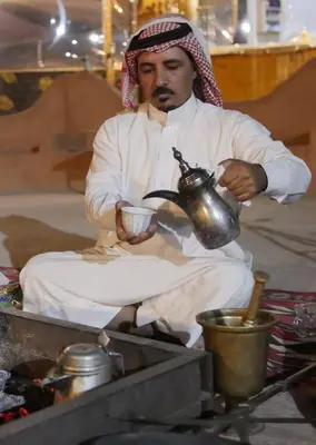 a man holding a teapot and a cup of coffee at Arena Desert Camp & Adventurers in Wadi Rum