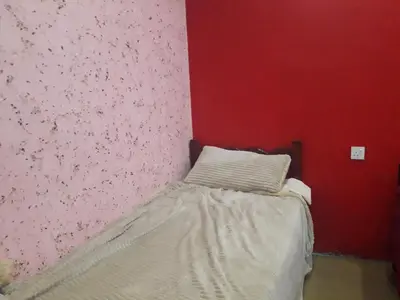 a small bed in a room with a pink wall at WadiRum Village Lodge in Wadi Rum