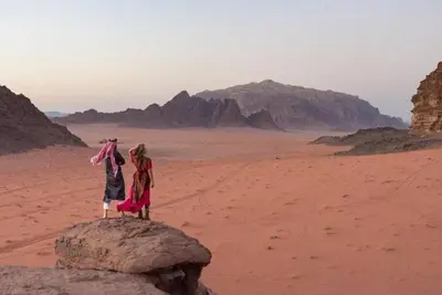 two people standing on a rock in the desert at WadiRum Mobile Camp in Wadi Rum