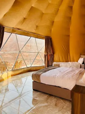 a bed in a room with a large window at sand magic camp in Wadi Rum