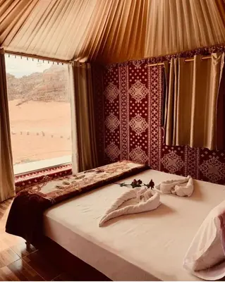 a bed in a room with a view of the desert at sand magic camp in Wadi Rum