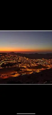 a view of a city with the sunset in the sky at Over Mountains Hotel in Wadi Musa