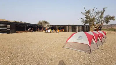 a row of tents sitting in a dirt field at Wadi Ghwere Camp مخيم وادي الغوير in Al Khuraybah