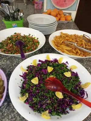 three plates of food on a table with plates of food at Petra Cabin Hostel in Wadi Musa