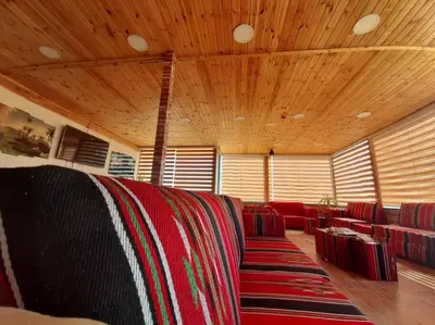 a room with a couch with red chairs and wooden ceilings at Petra Cabin Hostel in Wadi Musa