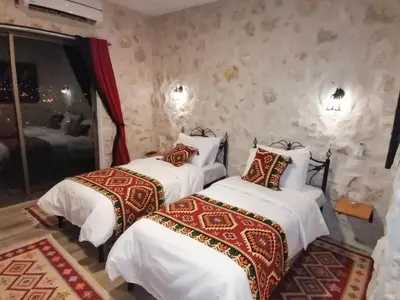 a bedroom with two beds with white sheets and red pillows at Infinity Lodge in Wadi Musa