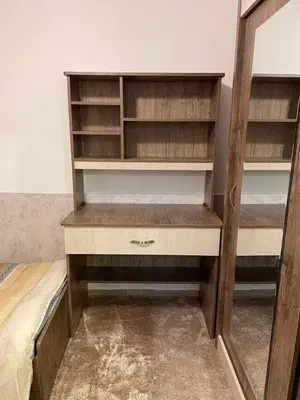 a closet with wooden shelves and a bed at شركة مسايا لشقق المفروشة in Irbid