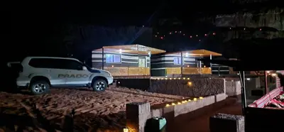 a white truck parked in front of a building at night at Wadi Rum Quiet Sky in Wadi Rum