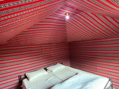 a room with a red and white striped wall with a bed at Wadi Rum Quiet Sky in Wadi Rum