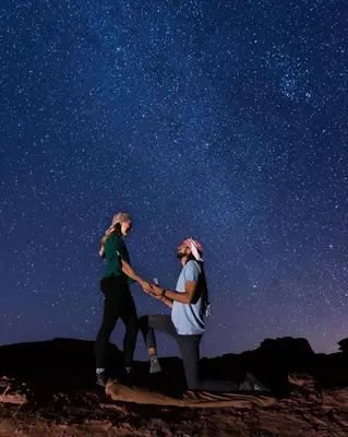 a couple of people holding hands under a starry sky at Wadi Rum Quiet Sky in Wadi Rum