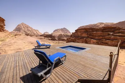 a deck with chairs and a swimming pool in the desert at Palmera Camp Wadi Rum in Wadi Rum