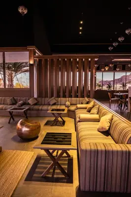 a living room with couches and tables and windows at Palmera Camp Wadi Rum in Wadi Rum