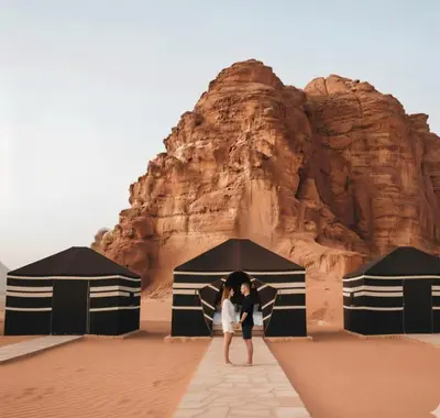 a couple standing under an umbrella in the desert at One Thousand and One Nights Camp in Wadi Rum