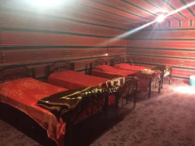 a room with four beds with red sheets at Wadi Rum in Wadi Rum