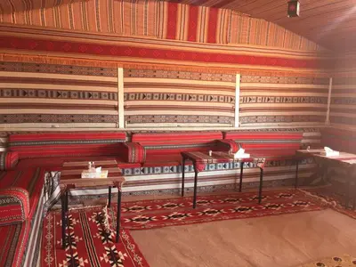 a room with red and white carpeted walls and tables at Wadi Rum in Wadi Rum