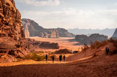 a group of people walking down a dirt road in the desert at Rum Panoramic Camp & Tour in Wadi Rum