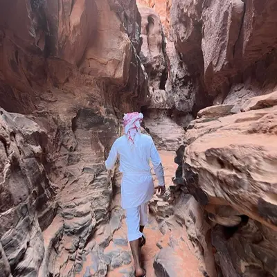 a man walking through a canyon in the desert at Rum Panoramic Camp & Tour in Wadi Rum