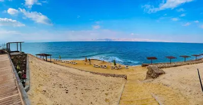 a beach with chairs and umbrellas and the ocean at O Beach Hotel & Resort in Sowayma