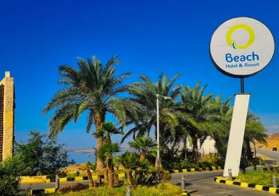 a sign for the beach hotel and resort with palm trees at O Beach Hotel & Resort in Sowayma