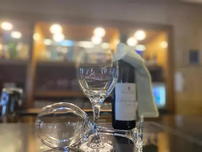two wine glasses sitting on a counter with a bottle of wine at O Beach Hotel & Resort in Sowayma