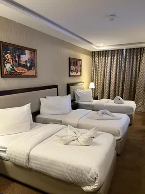 a hotel room with three beds with white sheets at Strand Hotel Jordan in Amman