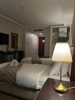 a hotel room with a bed and a table with a lamp at Strand Hotel Jordan in Amman