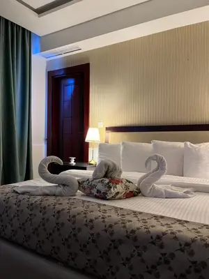 a bedroom with a bed with two swan pillows on it at Strand Hotel Jordan in Amman